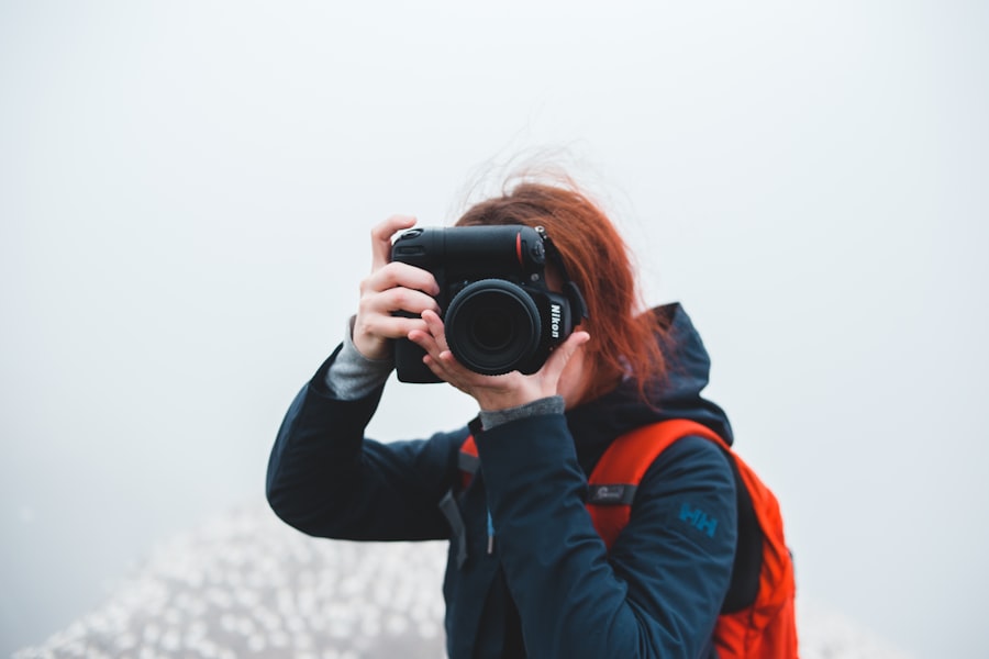 woman in black and orange jacket holding black camera