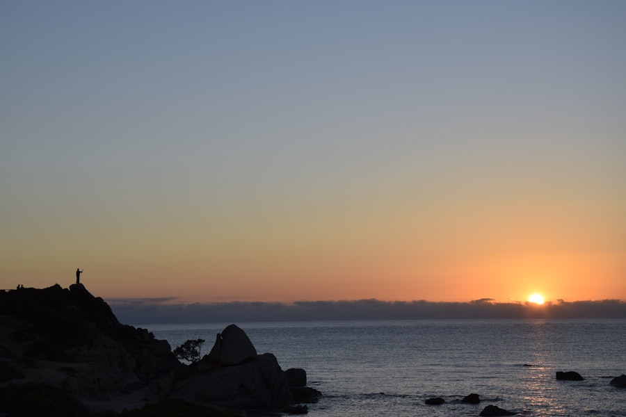 Sunrise over the ocean with silhouette on rock.