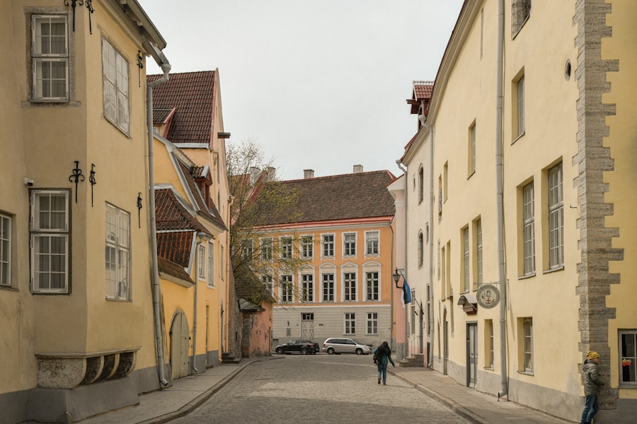 Narrow cobblestone street with yellow historic buildings and a person.