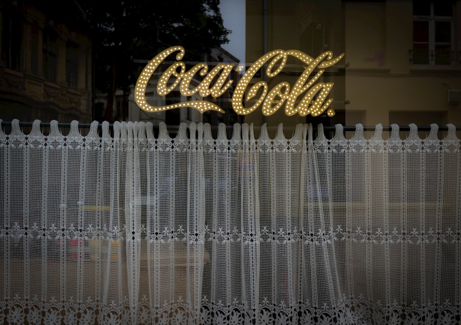 Coca-cola sign lit up behind lace curtains