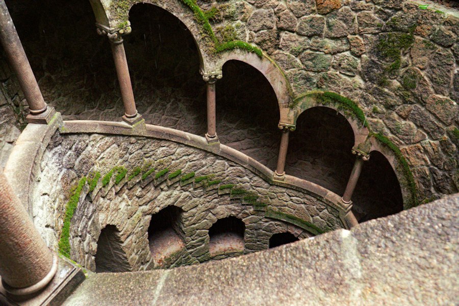 Ancient stone spiral well with moss-covered arches and pillars