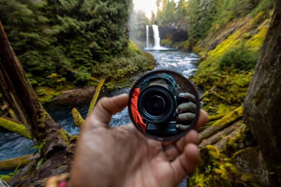 a person holding a camera in front of a waterfall