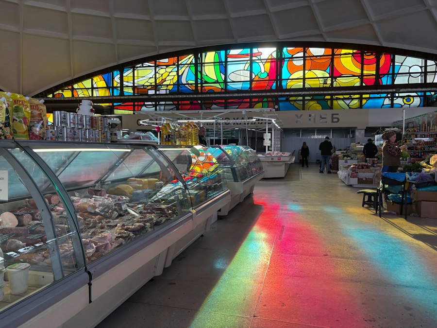Colorful stained glass illuminates a market hall with food displays