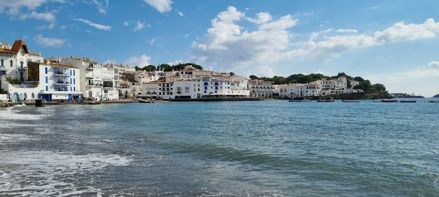 White buildings line a blue bay under a cloudy sky