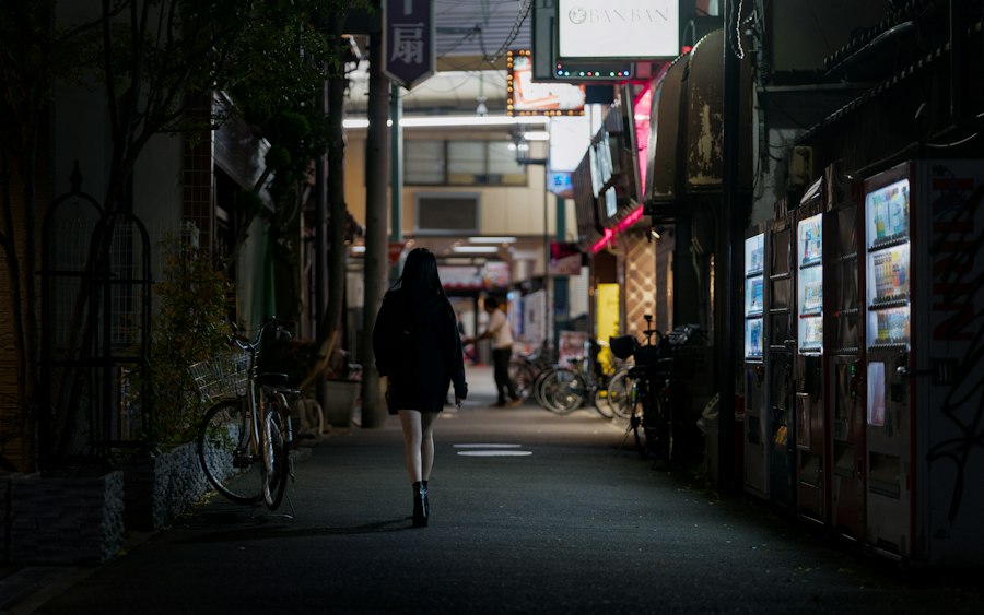 A person walks down a dark, narrow street at night