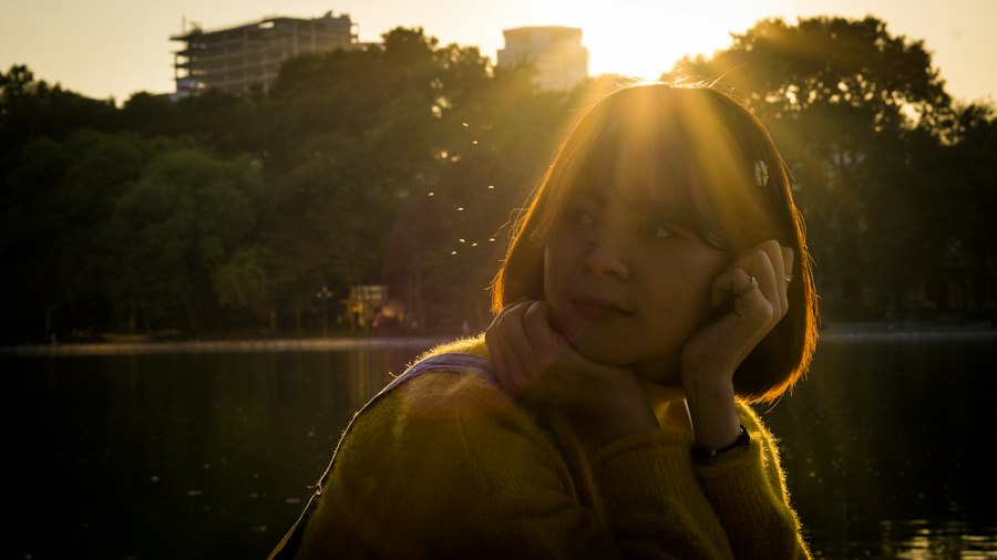 a woman standing in front of a lake while talking on a cell phone