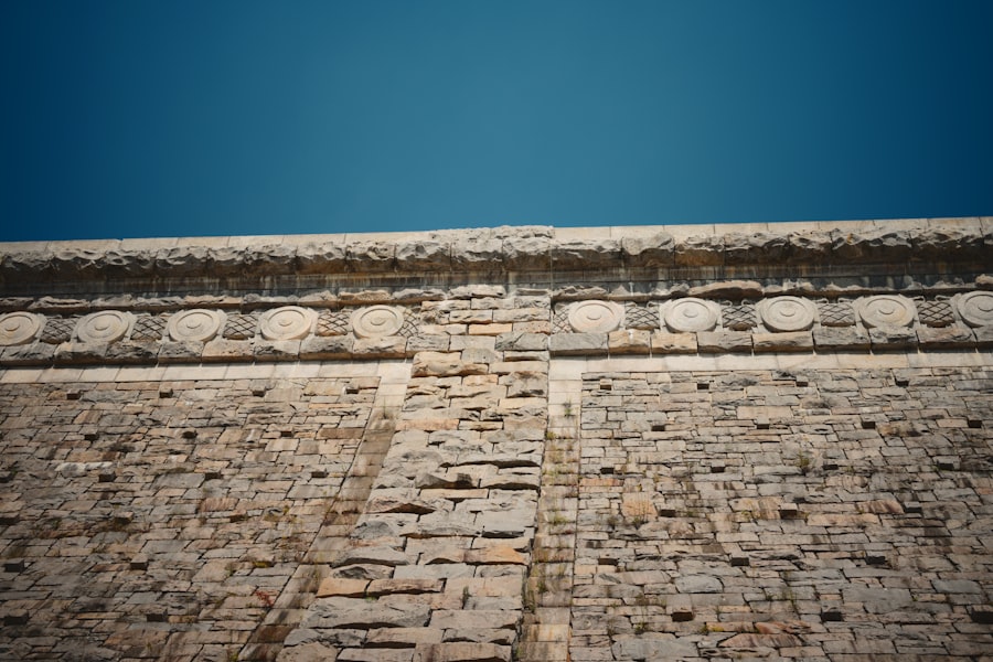 An ancient stone wall with carvings against a blue sky.