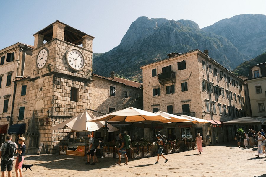 Old town square with clock tower and mountains