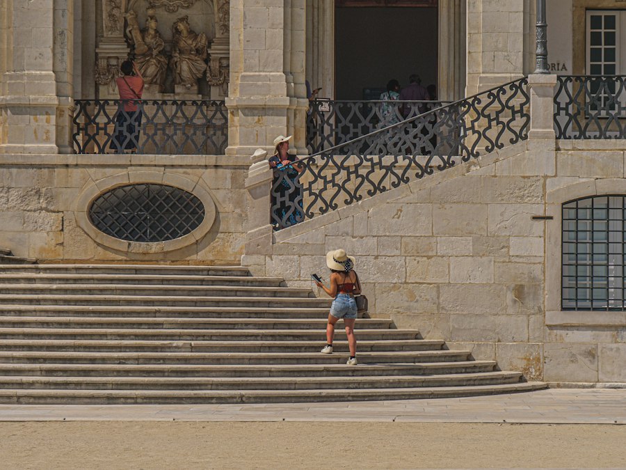 Woman in hat walks up stone stairs outside stairs