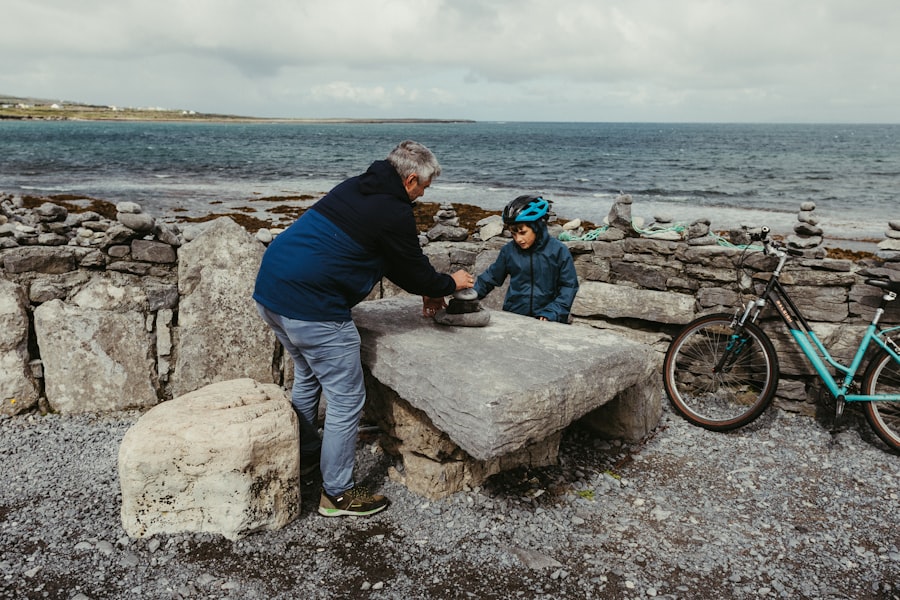 Man and child interacting at stone table by the sea.