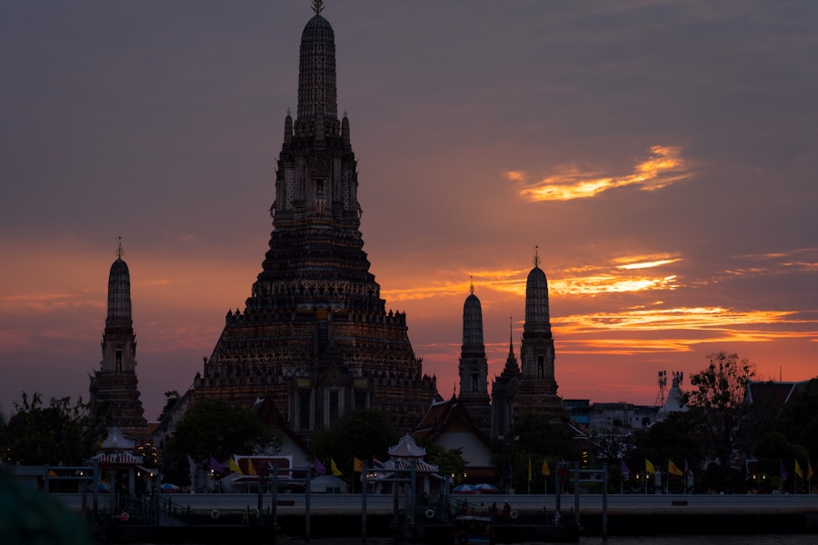 Wat arun temple towers against a dramatic sunset.