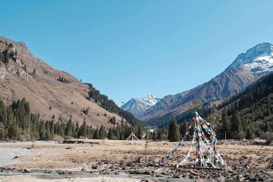 Prayer flags flutter in a mountain valley with snow-capped peaks.