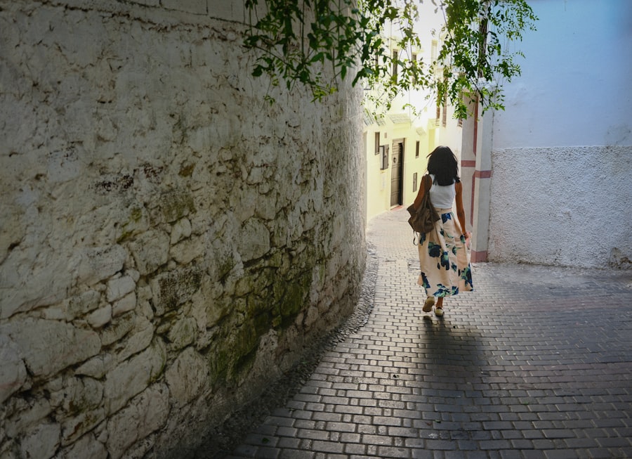 Woman walking down a sunlit cobblestone alleyway.