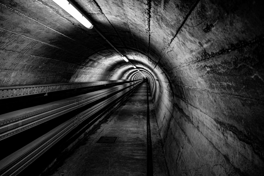 A dark, empty concrete tunnel with lights overhead.