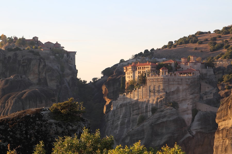 Monastery perched on rocky cliffs at sunset.