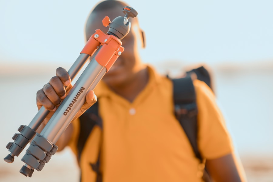 man holding silver and red Manfrotto tripod