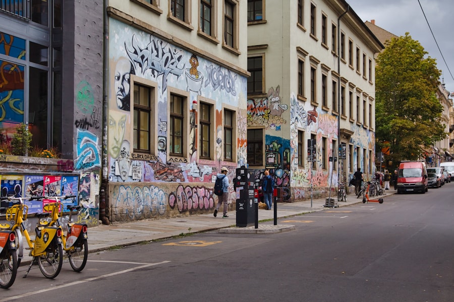 People walking on a sidewalk past buildings covered in colorful street art graffiti