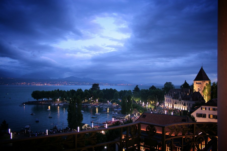 City lights reflect on a calm lake at dusk