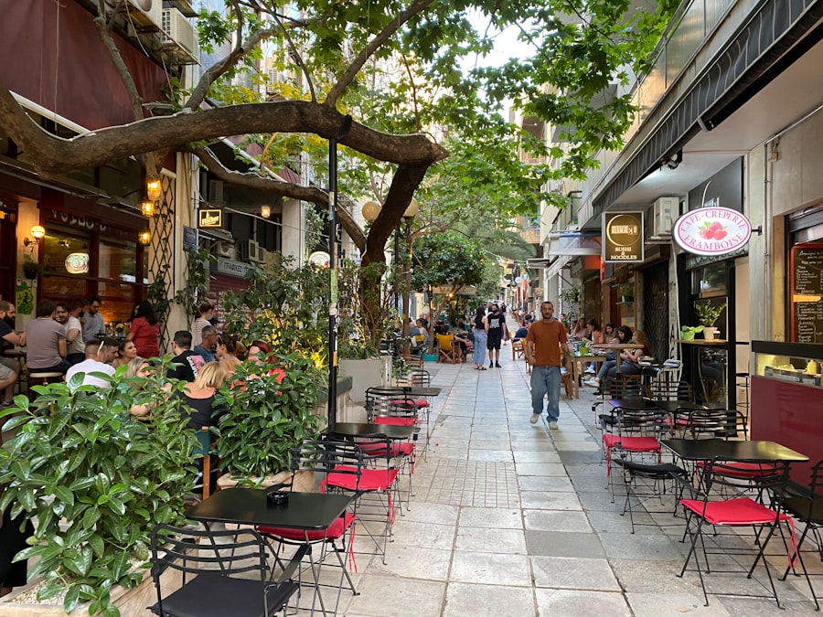 a group of people walking down a sidewalk next to tables and chairs