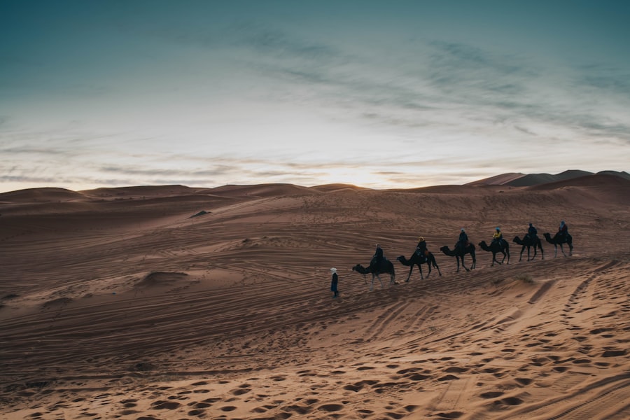 Camels and riders traverse the desert dunes.