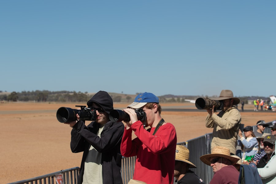 Three photographers with telephoto lenses capture an event outdoors.