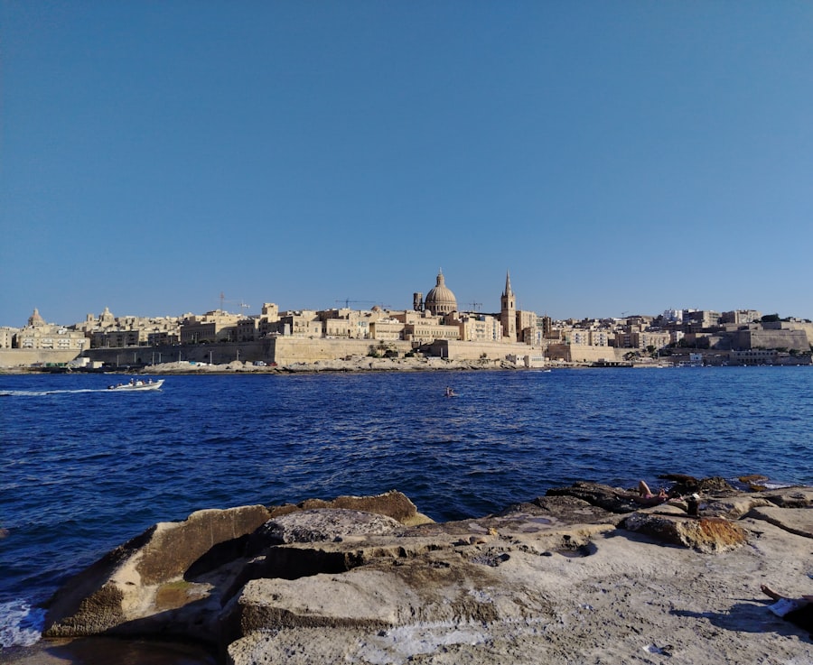Valletta city skyline across blue water with a boat.
