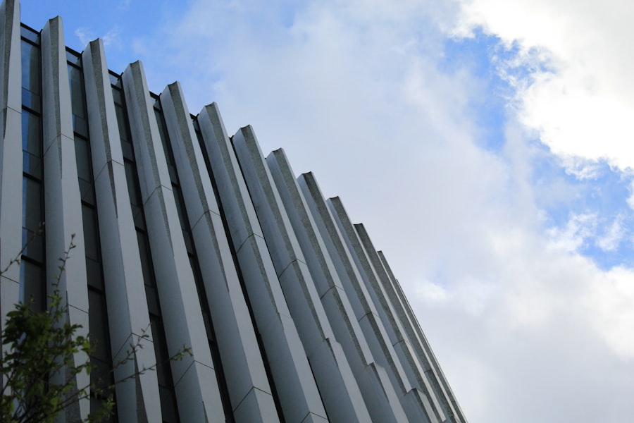 Modern building facade with vertical ribs against a cloudy sky.