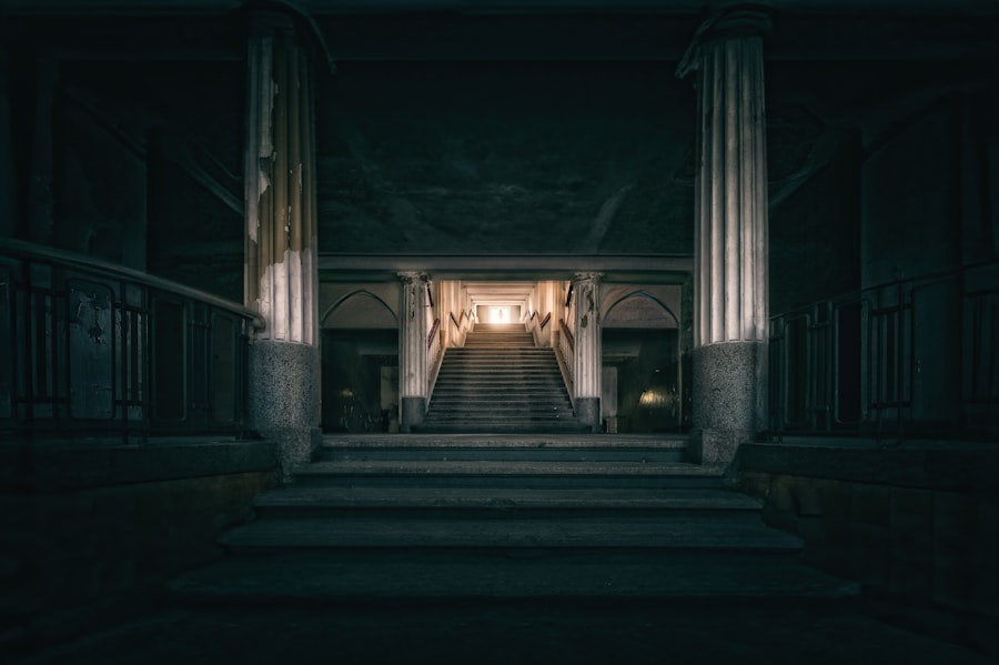 Grand staircase leading to bright light in a dark building.